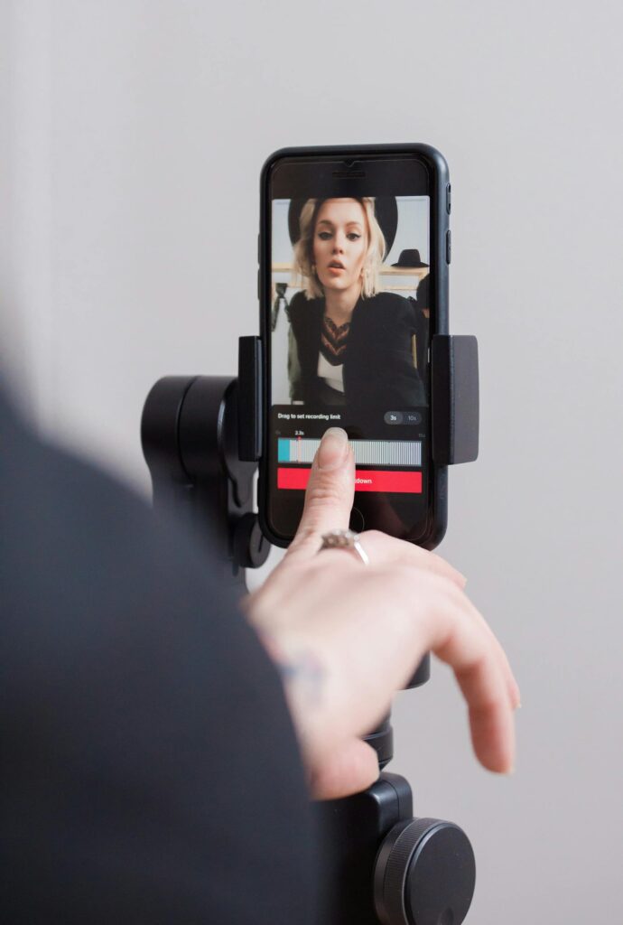 A woman recording a vertical video on her smartphone, focusing on engaging digital content creation.